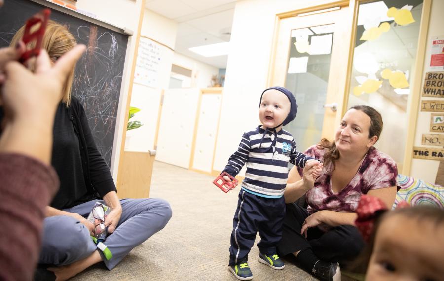 A mother and toddler listening to teacher. 