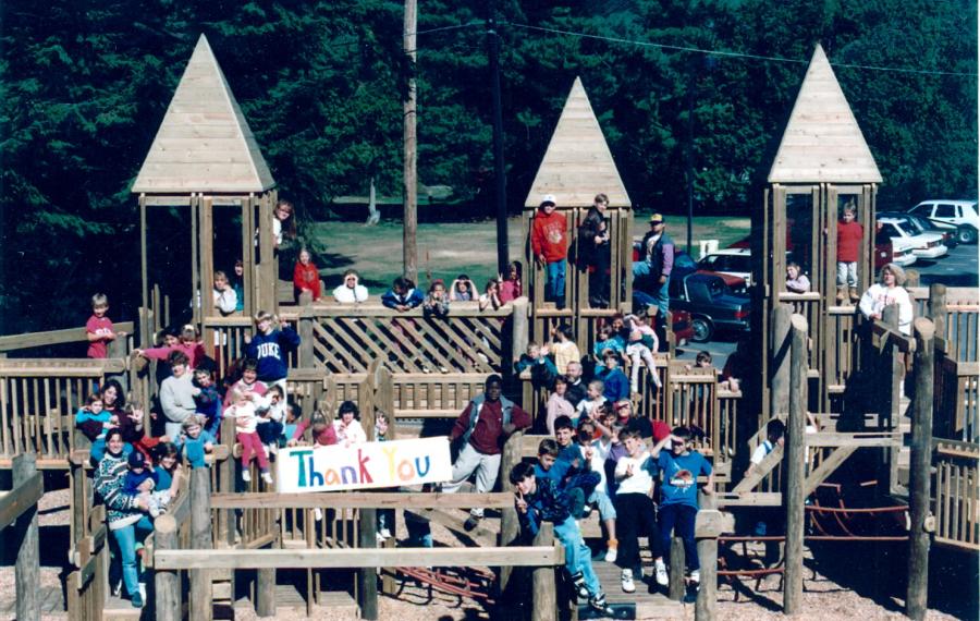 Group of students holding a sign saying thank you at the playground. 