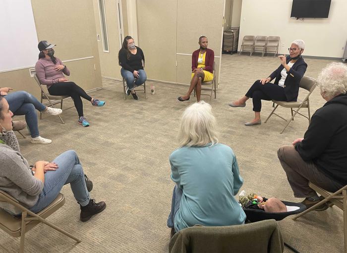  A group sitting in a circle on chairs.