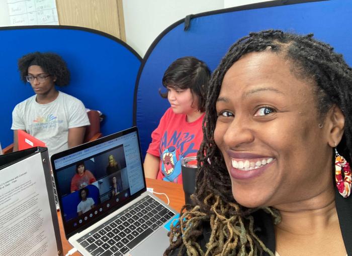 TLC Superintendent Glennis Matthews in the foreground; in the background, two students looking at laptops.