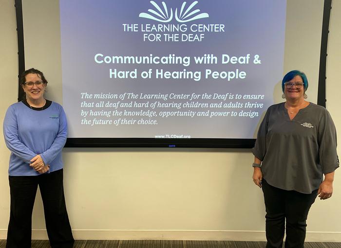 Karen Bishop and Keri Darling stand on either side of a projector.