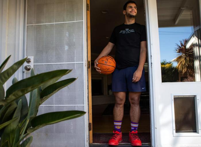 Kade West stands in the doorframe of his aunt’s home before he playing basketball in Long Beach