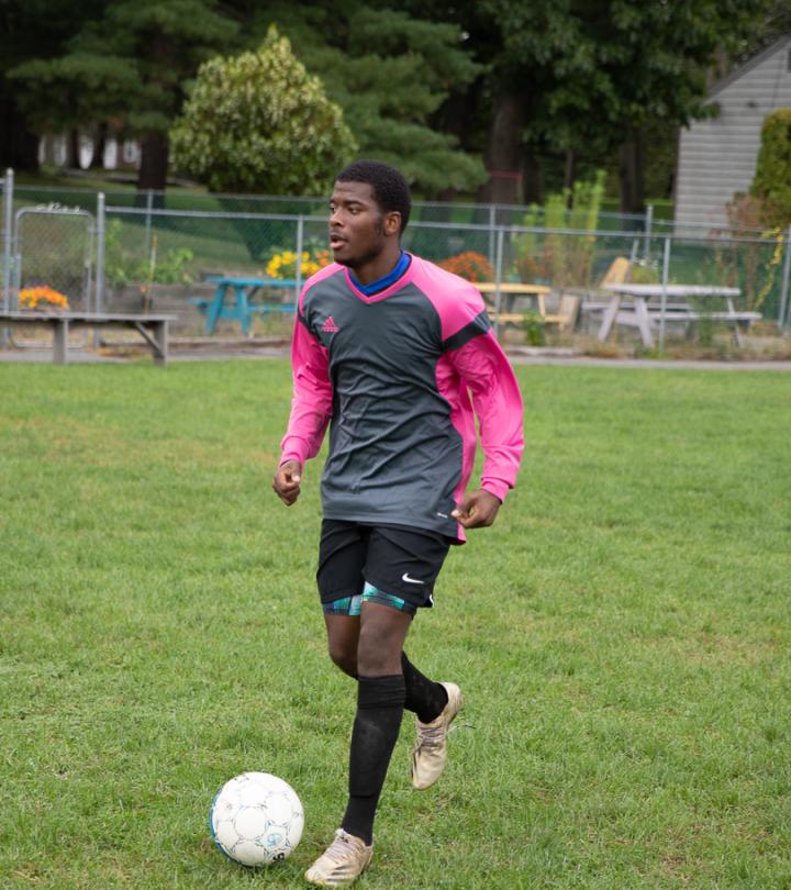 A student kicks a soccer ball outside.