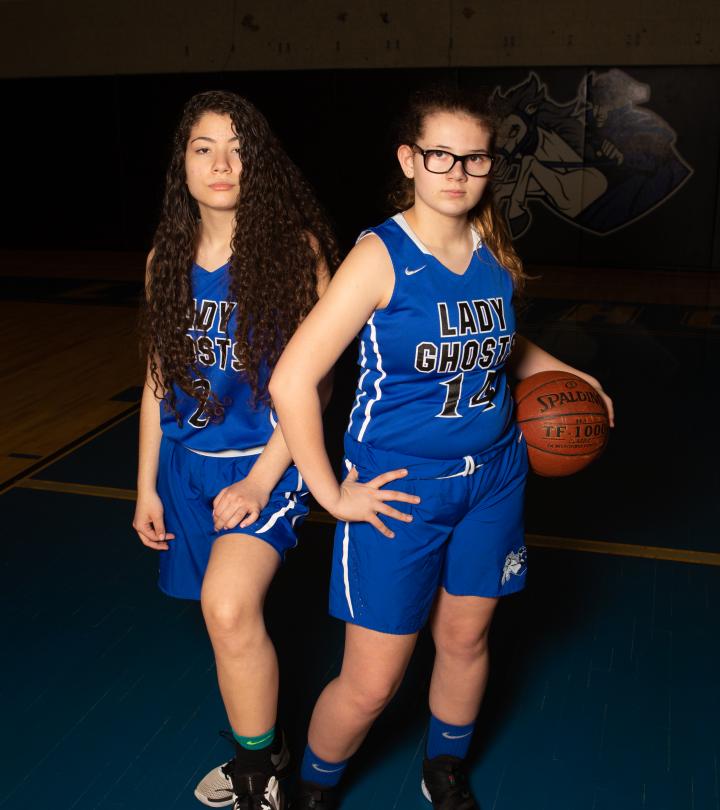 Two girls basketball players standing with basketball ball.