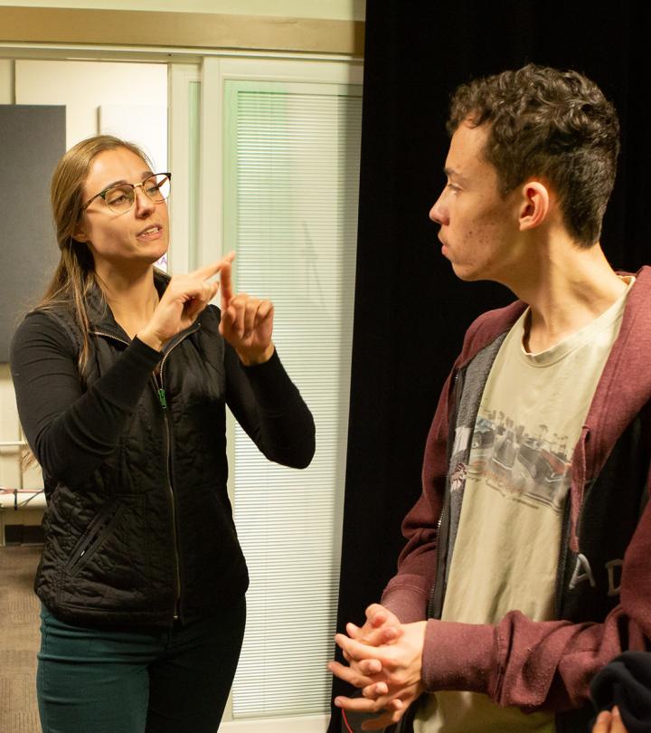 A young female on the left using American Sign Language. On the right a young male looking in her direction.