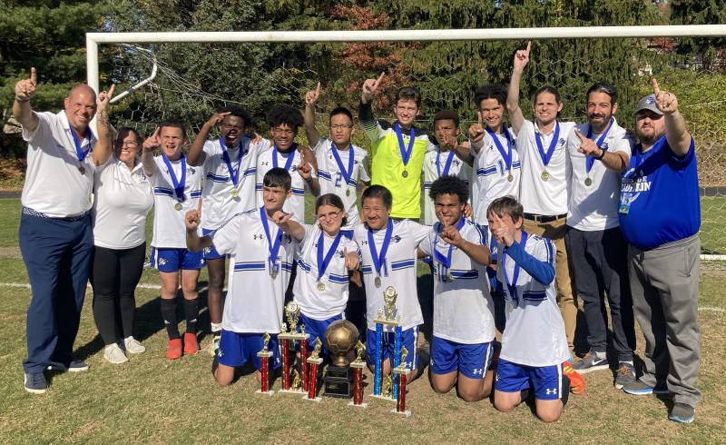 The MPWS Boys Soccer Team in a group photo. All are celebrating or holding up the Number 1