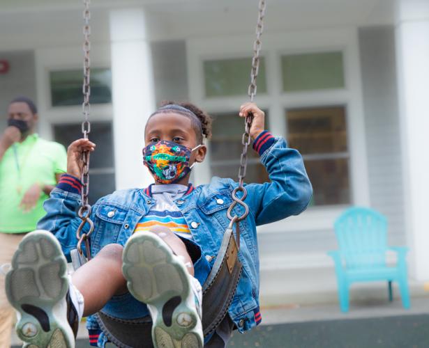 A young student is swinging. He is wearing a face mask.