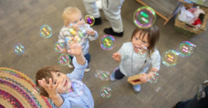 Two PIP students looking up a bubbles being blown in a classroom.