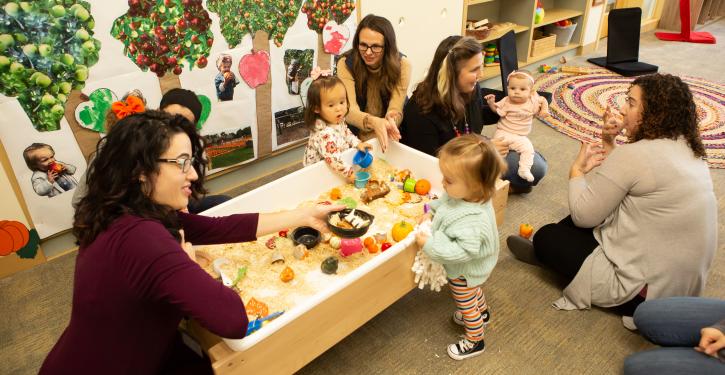 Group of parents and toddlers chatting in the playroom.