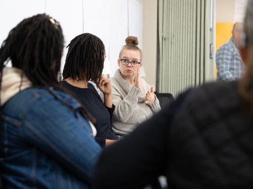 a white female with tan sweater talking to staff 