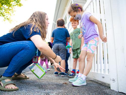 A teacher and a student outside. The Teacher is crouched down and the student is looking at her shoes.