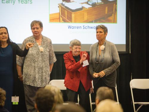 Maureen O'Donnell stands in the center of the photo in a red blazer. She is surrounded by other TLC staff,