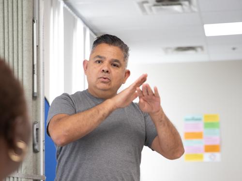 male with grey shirt talking to a female. 