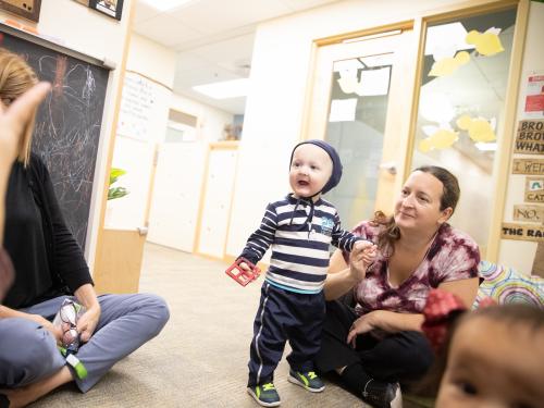 A mother and toddler listening to teacher. 