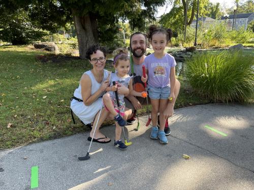 A family smiling together on a miniature golf course