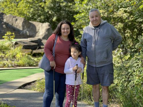 A family standing on a miniature golf course and smiling.