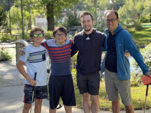 Four students standing side by side outside and smiling.