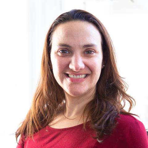 A white woman with long dark hair and a red dress. White for background.