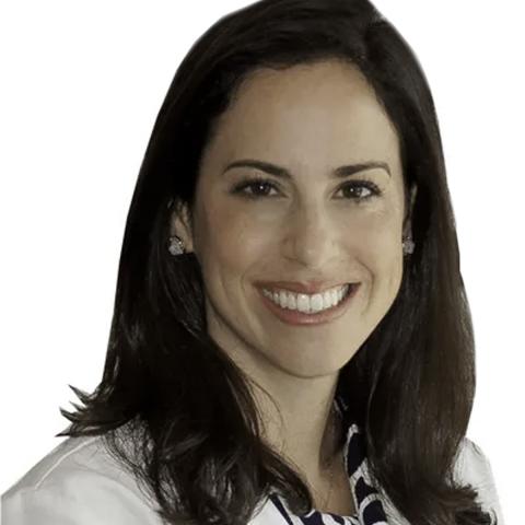 A white woman smiling at the camera. Medium length brown hair and a white blazer.